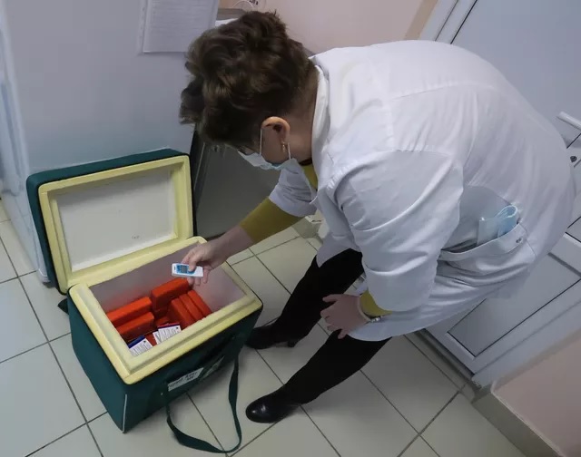 Медицинский работник измеряет температуру в контейнере, где хранится российский препарат "Гам-Ковид-Вак" для вакцинации жителей деревни в Тульской области