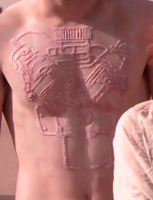 На теле Накса - шрамовая татуировка двигателя внутреннего сгорания в разрезе. Он живет своим служением водителя
