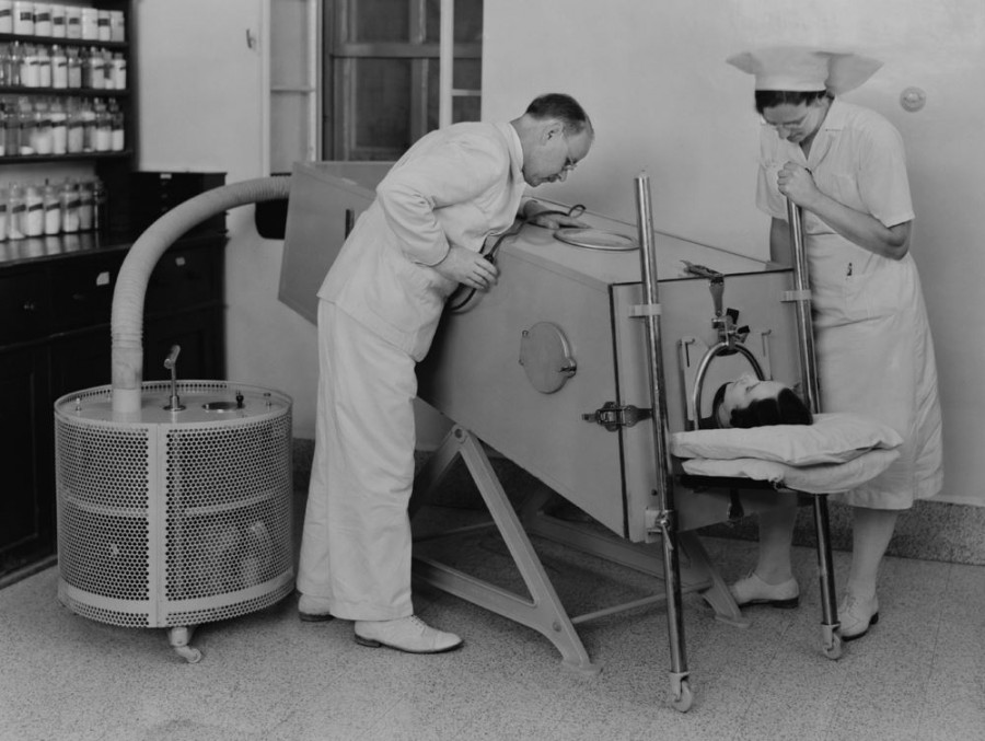 На фотографии - так называемые "железные легкие", устройство, предназначенное для того, чтобы человек, парализованный в результате перенесенного полиомиелита, мог дышать